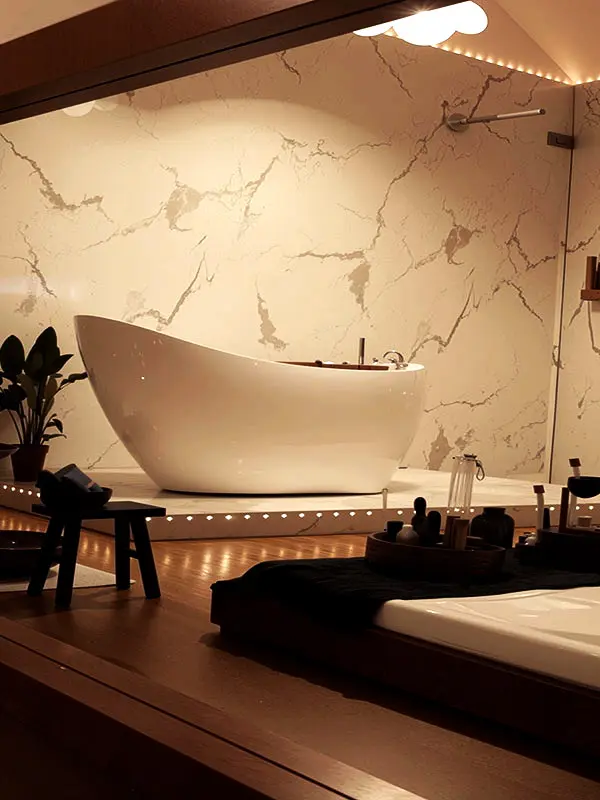 Sala de tratamento com parede em m&aacute;rmore, banheira e marquesa de massagem, exemplo de um espa&ccedil;o profissional em Lisboa