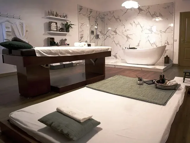 Sala de massagem profissional com marquesas, parede em m&aacute;rmore e banheira