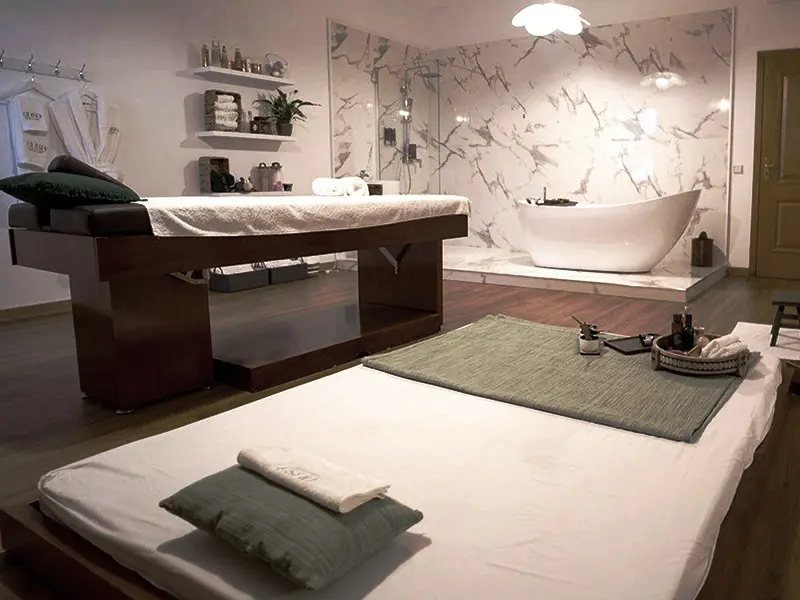Sala de massagem profissional com marquesas, parede em m&aacute;rmore e banheira