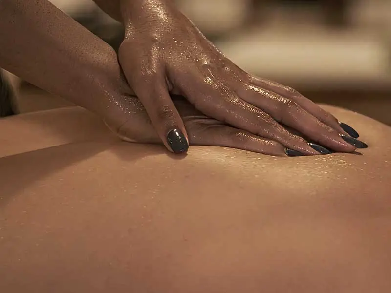 M&atilde;os de massagista com &oacute;leo morno durante uma massagem no Nusa Massage Spa em Lisboa