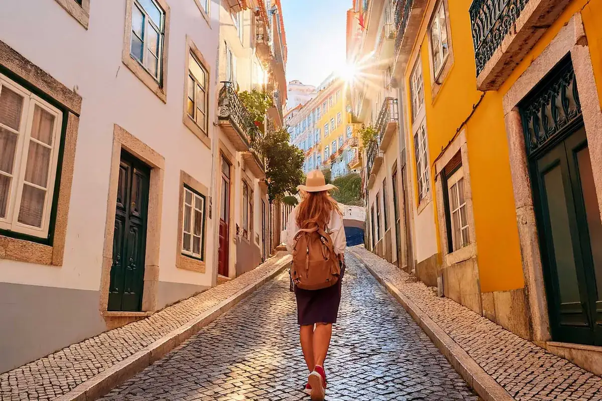 Turista a explorar uma rua t&iacute;pica e colorida de Lisboa